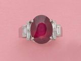 gros plan d'une bague avec une pierre rouge entourée de diamants blancs