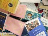 a pile of books on a bed with a blue and white blanket