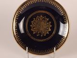 une assiette noire et dorée ornée d'un motif doré