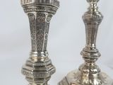 pair of silver candlesticks on a white surface with a white background