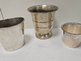 trois vases en argent posés les uns à côté des autres sur une table