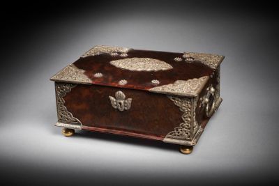 une boîte en bois richement décorée, ornée de motifs métalliques sur une surface grise