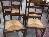 quatre chaises en bois disposées dans une pièce dont le sol est recouvert d'un tapis