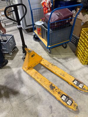 un homme debout à côté d'un chariot élévateur dans un entrepôt