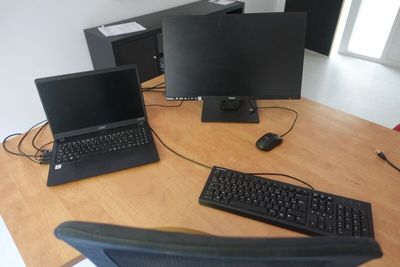 three laptops and a keyboard on a wooden desk