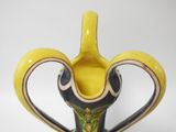 a yellow and black vase with a heart shaped handle