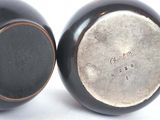 pair of black vases sitting on top of each other on a white surface