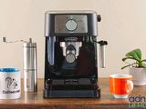 a black coffee machine sitting on a wooden table next to two cups