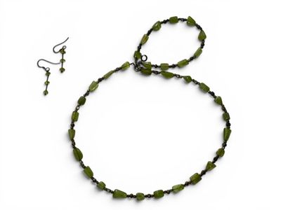 a close up of a necklace and earrings on a white surface