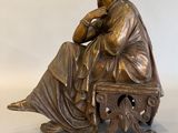 une photo d'une statue en bronze représentant une femme assise sur un banc