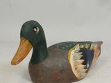 a wooden duck that is sitting on a white surface