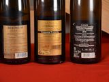 three bottles of wine sitting on a red cloth