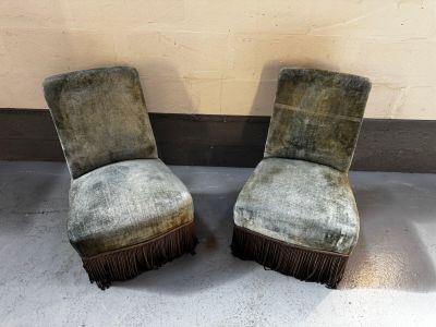 une paire de fauteuils en velours vert ornés de franges, placés devant un mur