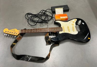 une guitare posée sur une table à côté d'une sangle de guitare