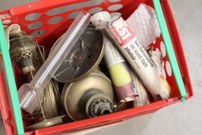 un panier rouge rempli d'objets divers, posé par terre
