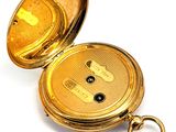 a gold pocket watch with a key in it