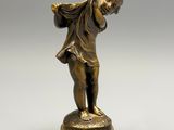 une figurine antique en bronze représentant un garçon sur un socle