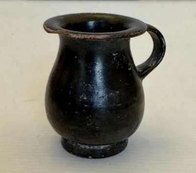 un vase noir posé sur une table, sur fond blanc