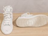white high top sneakers with laces on a wooden surface