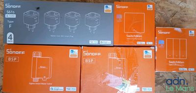trois boîtes contenant des téléphones orange et noirs, posées sur un plancher en bois