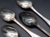 three silver spoons and two silver spoons on a black surface