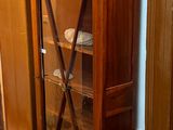 a wooden cabinet with a glass door in the corner of a room