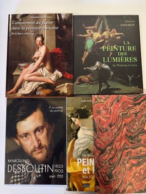 quatre livres posés sur une table où est accroché un tableau représentant un homme et une femme