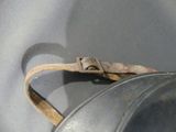a metal pot with a handle and a leather strap on it