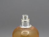 un flacon de parfum posé sur une table, sur fond gris