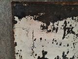 a rusted metal sign on the wall of a building