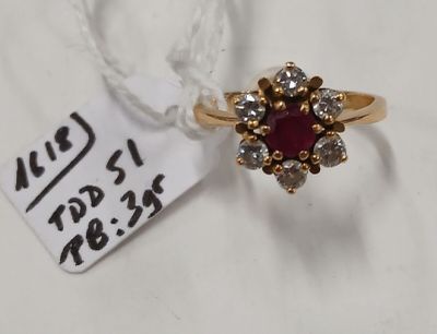 un gros plan d'une bague en or sertie d'une pierre rouge entourée de diamants