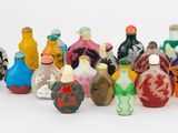 de nombreuses bouteilles en verre de différentes couleurs posées sur une surface blanche