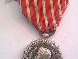 une médaille d'argent entourée d'un ruban rouge et blanc