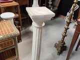 a white pedestal in the middle of a room filled with antiques
