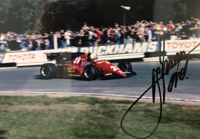 signed photograph of a man driving a racing car on a race track