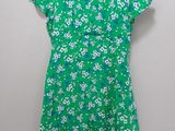a green dress with white flowers on it hanging on a hanger