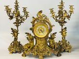 une horloge en or ornée d'anges et un candélabre