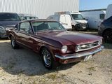 a red mustang parked in a lot with other cars