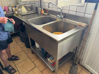 a man standing in a kitchen with a sink and a mop