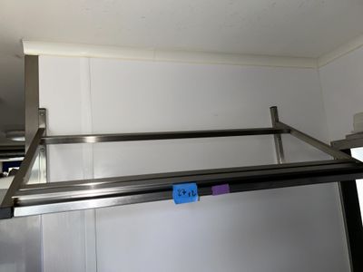 une photo d'une étagère en acier inoxydable sur laquelle est accrochée une étiquette bleue