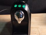 une cafetière noire posée sur une table en bois, à côté d'une tasse