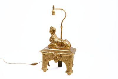 une statue en or posée sur une table sur laquelle se trouve une lampe