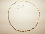 a close up of a gold necklace on a white surface