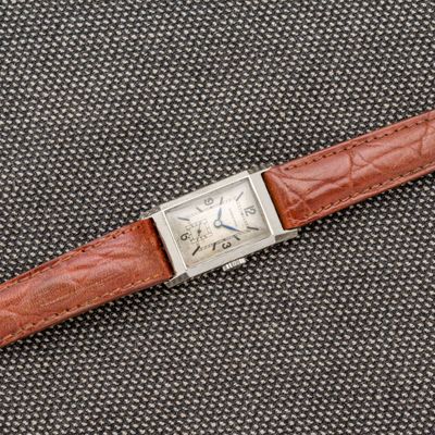 une photo d'une montre avec un bracelet en cuir marron posée sur une table