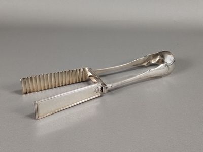paire de pinces plaquées argent avec des manches, posées sur une surface grise