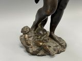 bronze statue of a boy holding a bird on a rock