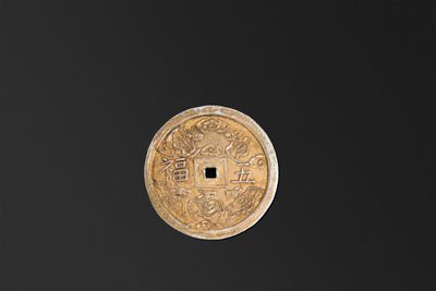 une vieille pièce chinoise posée sur une surface noire, sur fond noir