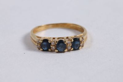 un gros plan d'une bague en or sertie de trois saphirs
