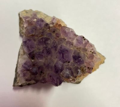 un améthorate violet sur une surface blanche, avec un petit morceau de roche au premier plan