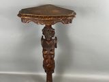 une table ancienne en bois dont le plateau est sculpté et sur lequel se trouve une figurine sculptée